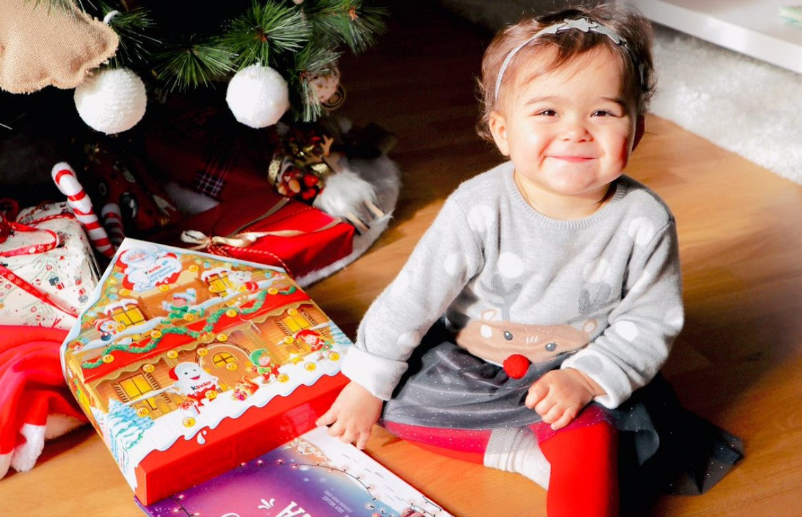 A little girl smiles after receiving a personalized christmas book as an xmas gift.