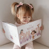 Little girl looking inside her personalized storybook where her mom is imagining the future with her child.