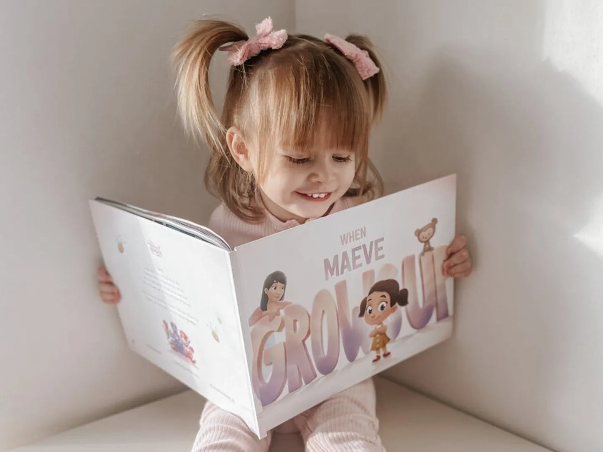 Little girl looking inside her personalized storybook where her mom is imagining the future with her child.