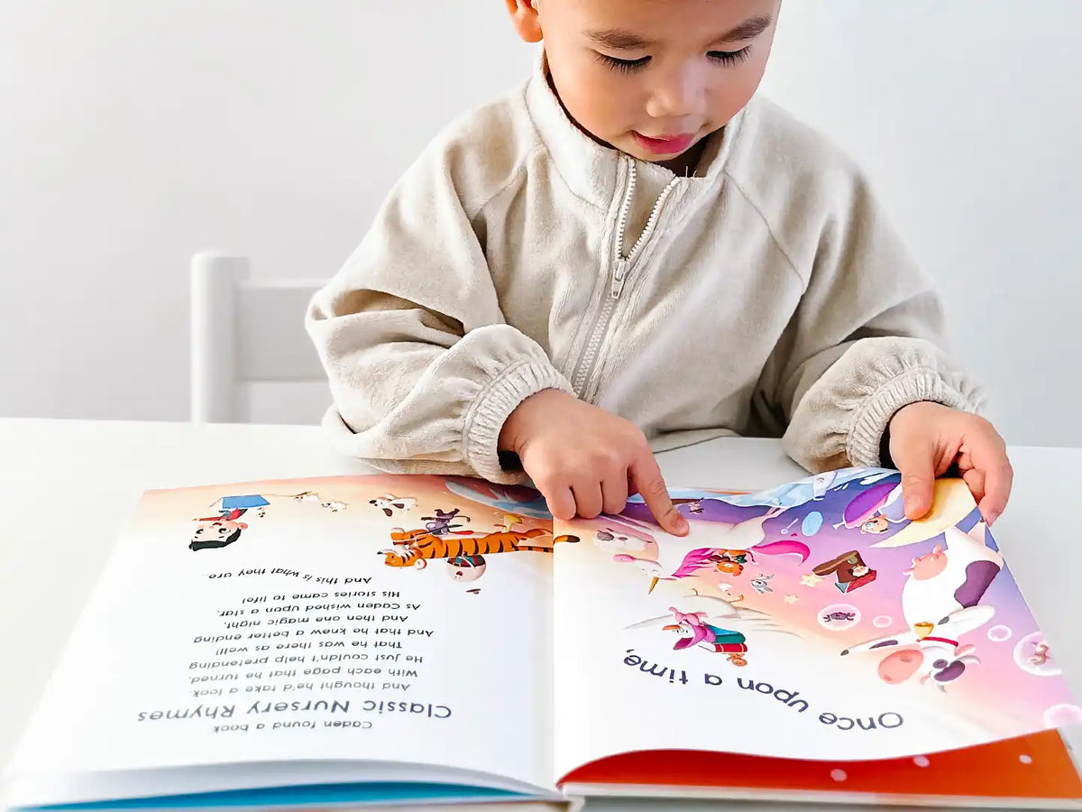 Boy with a cap is pointing to a fun colorful illustration from his customized nursery song book.