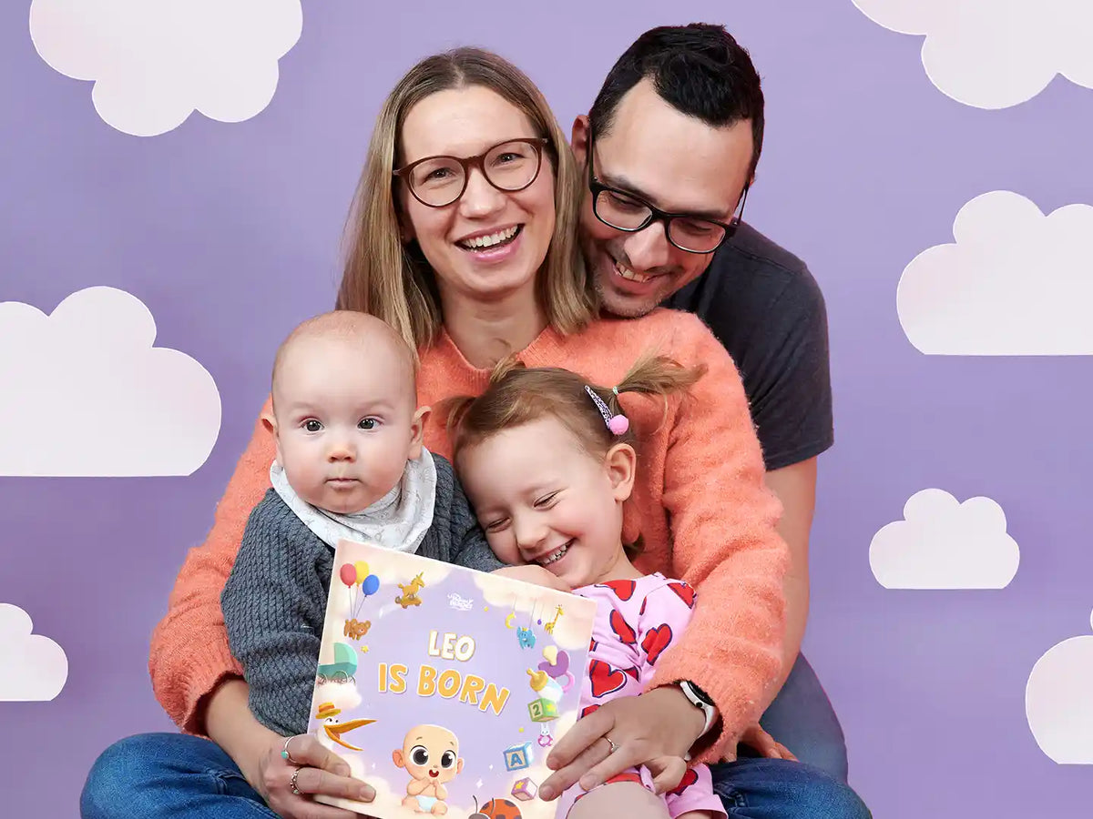 Family holding a personalized book for their new baby which they got as a present at birth.