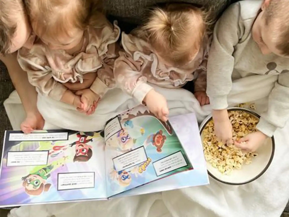 Kids eating popcorn and are enjoying this personalized book for brothers and sisters.