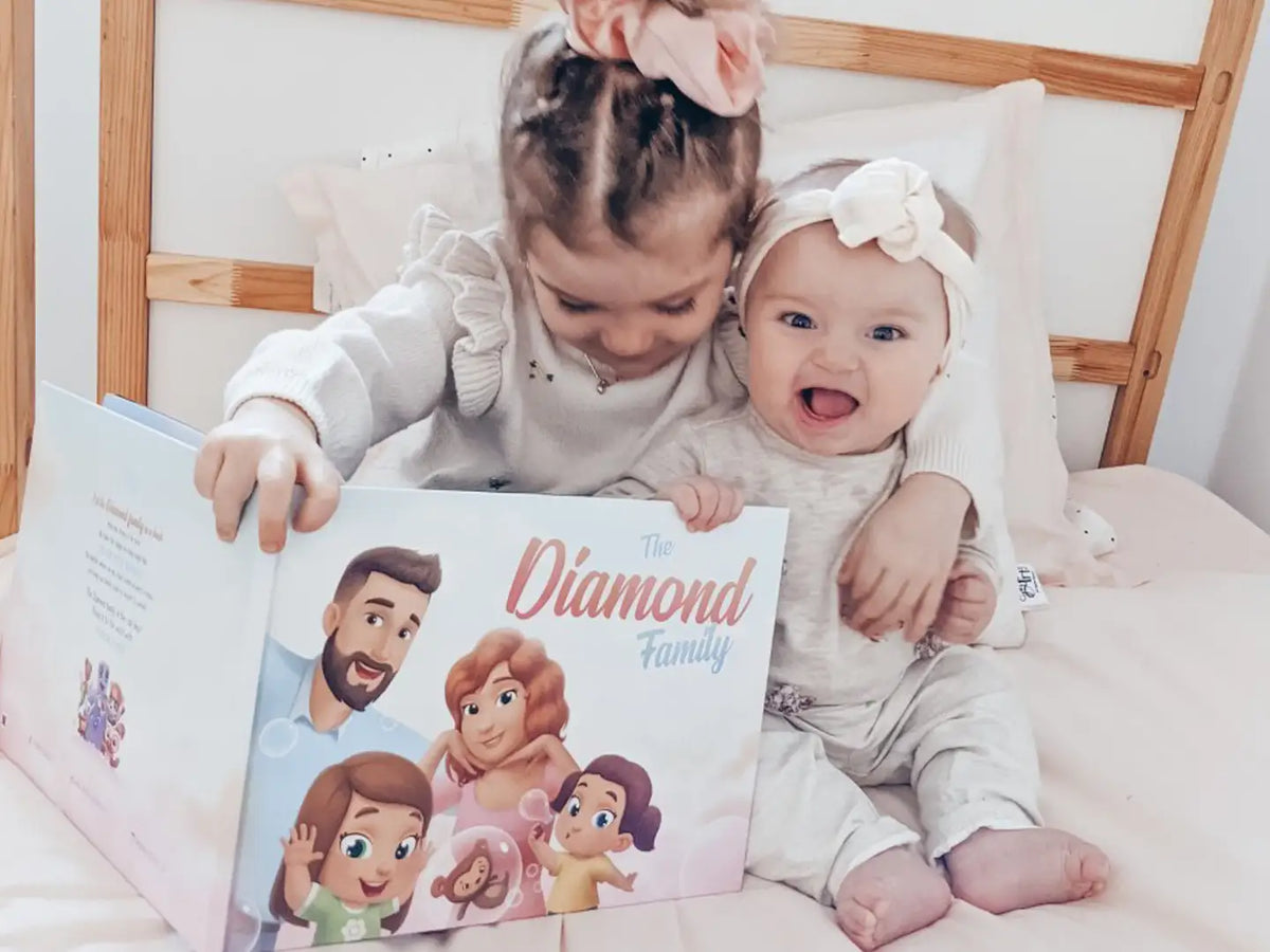 Two girls smiling while looking at personalized illustrations made just for their family.