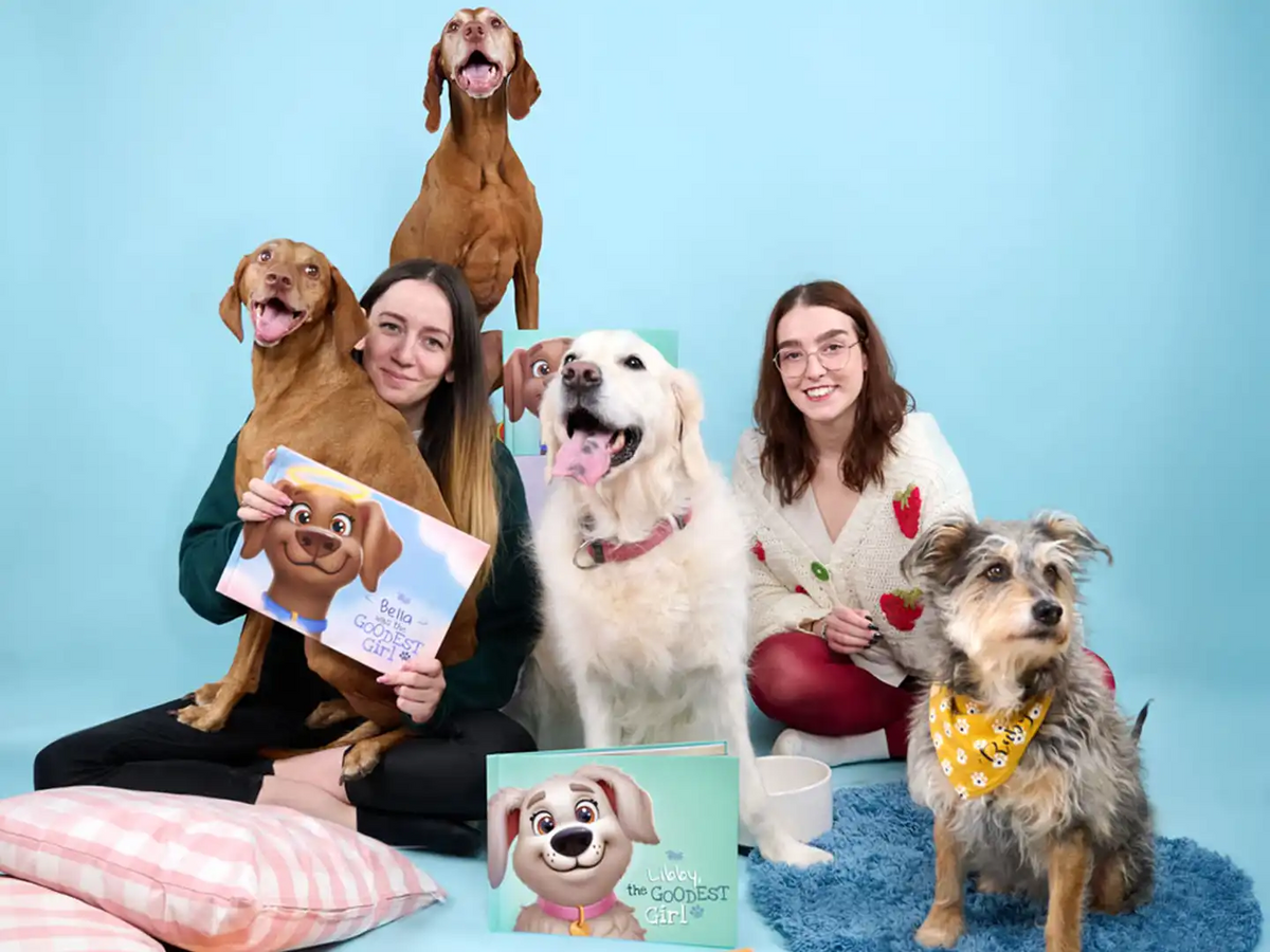 Pet owners and their dogs holding personalized dog books from Hooray Heroes, celebrating beloved pets with titles like 'Bella Was the Goodest Girl' and 'Libby the Goodest Girl'—a heartfelt memorial gift for dogs who’ve passed.