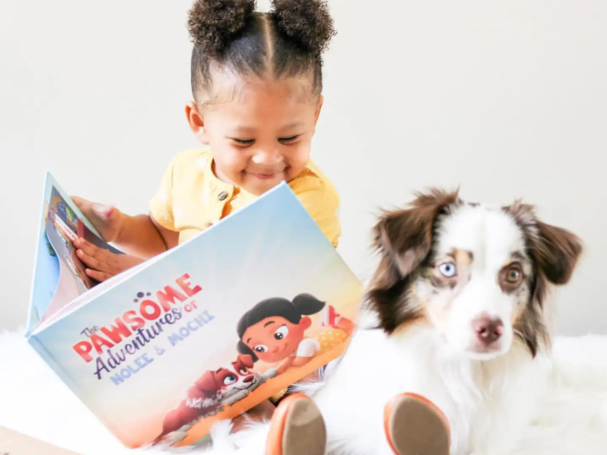 Little girl smiling at illustrations of her new personalized book made just for her and her pet dog Mochi.