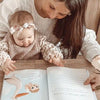 Little girl is looking at the customized book she got when she was born.