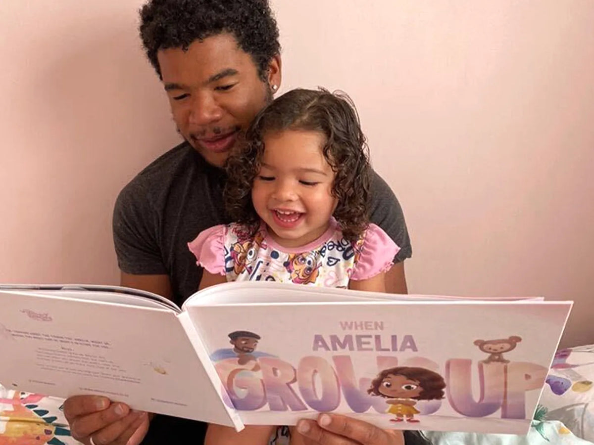 Girl is smiling while her dad is reading from a custom book they got for Christmas.