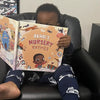 Boy is sitting and holding his book of nursery rhymes where we can see his personalized character and his name.