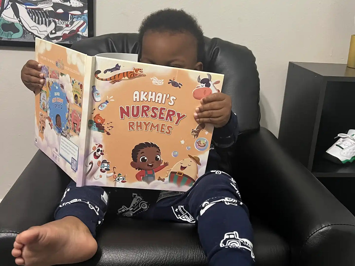 Boy is sitting and holding his book of nursery rhymes where we can see his personalized character and his name.