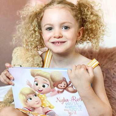 A girl with a Mother's Day present for mom, a unique DIY book for mothers and one kiddo.