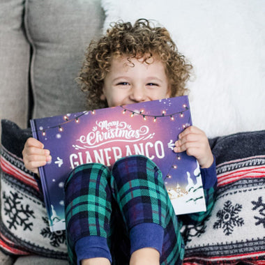 A child holds up their customized Christmas book from Hooray Heroes.