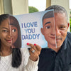 Daughter and dad are showing the similarities of the personalized characters on the cover of their custom-made book.
