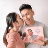 Woman is kissing a man who is holding a unique personalized book for Valentine's Day.