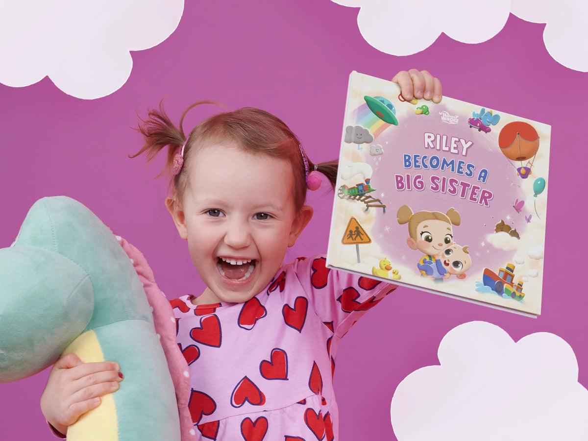 Happy girl proudly holding her personalized present, a book about becoming a big sister, after welcoming her baby brother.