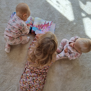Three sisters look at the illustrations in their unique DIY adventure book for kids, the perfect gift for 2 or 3 children.