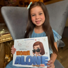 A girl is holding her personalized home alone book.