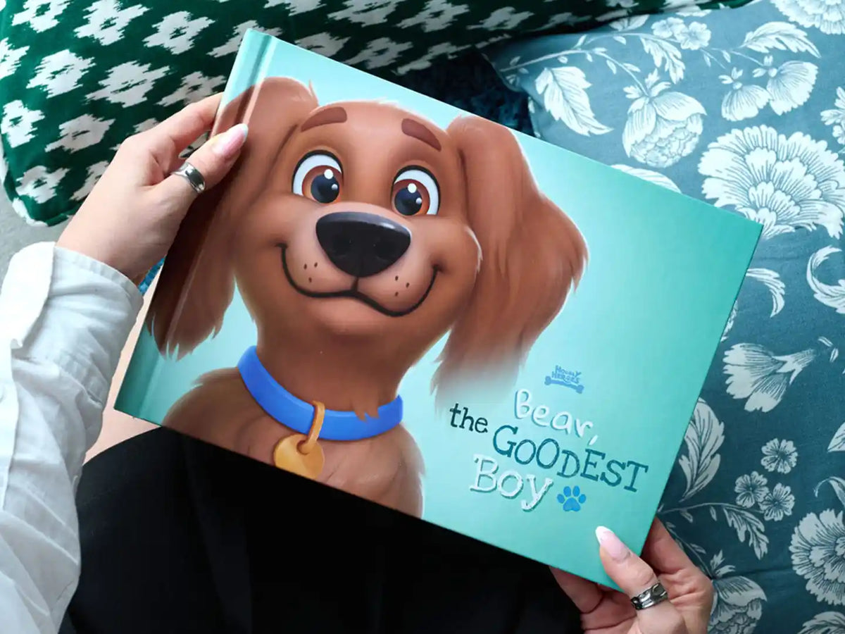 Person holding the dog book 'Bear the Goodest Boy' with a cute cartoon dog on the cover.