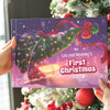 Person holding a personalized Christmas book titled “Leo and Mommy’s First Christmas 2025” in front of a decorated tree.