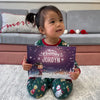 Girl is holding her custom storybook about Christmas which is the best gift under the Christmas tree.